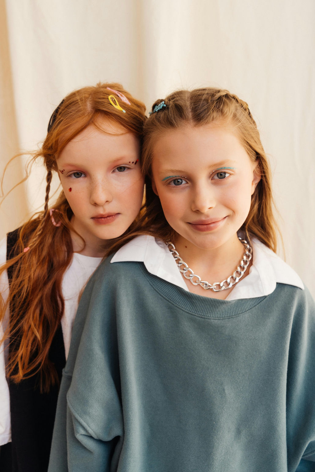 Dos niñas jóvenes con expresiones diferentes, una seria y otra sonriente, simbolizando emociones contrastantes en la infancia.