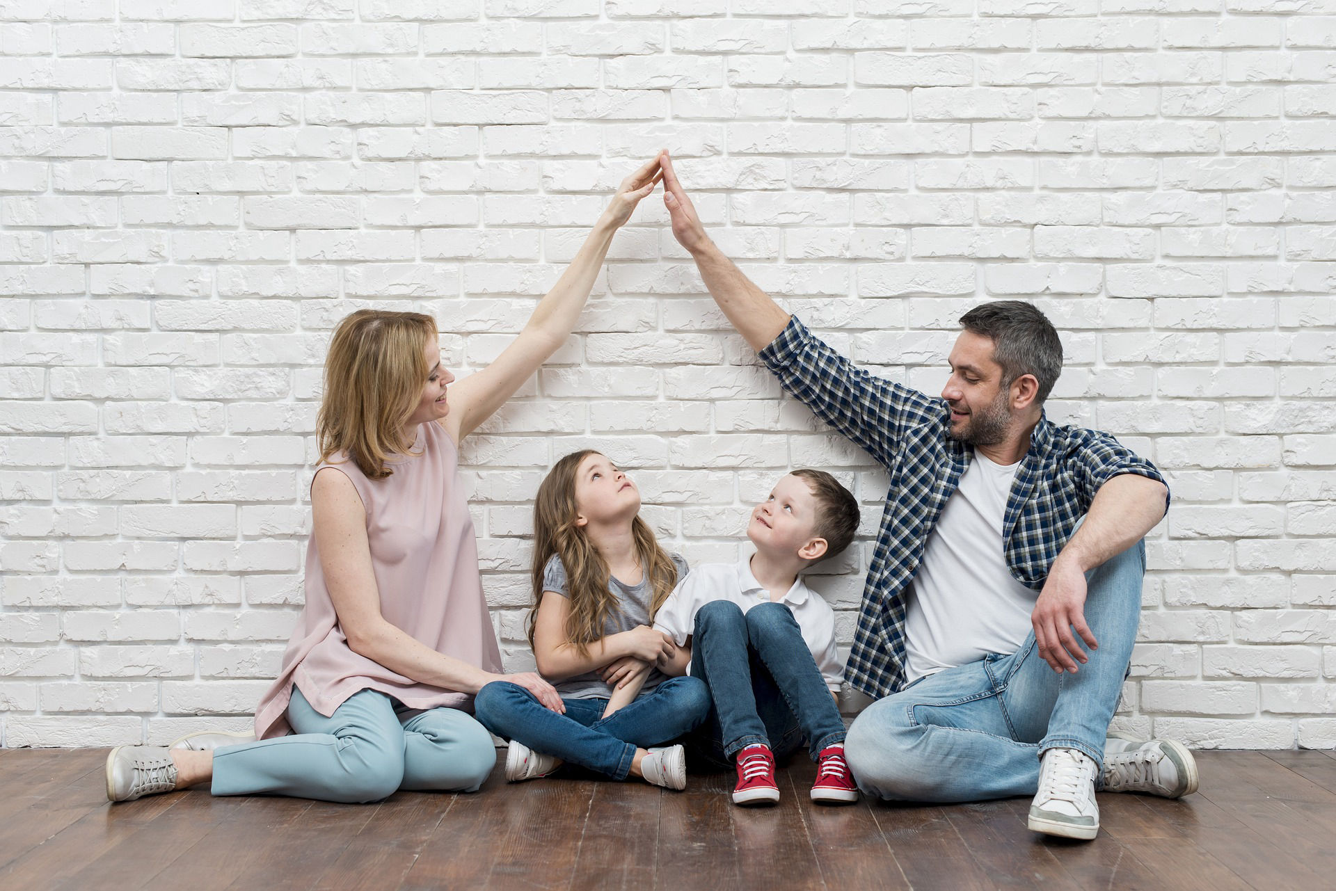 Padres separados haciendo un gesto de unión sobre sus hijos, representando la crianza compartida tras un divorcio.